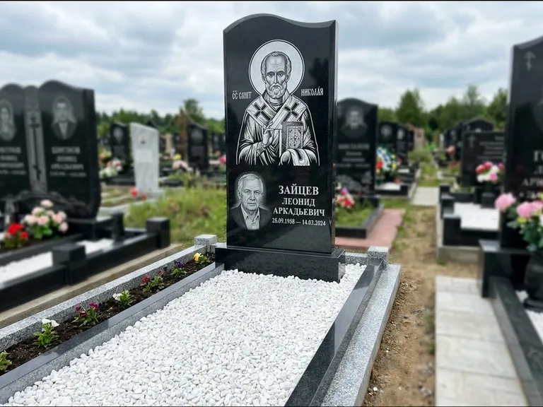 Памятник с гравировкой иконы: стела с крестообразным навершием — икона в резной рамке-киоте, газон без ограды, стриженая трава, работа «Раевская» в Челябинске