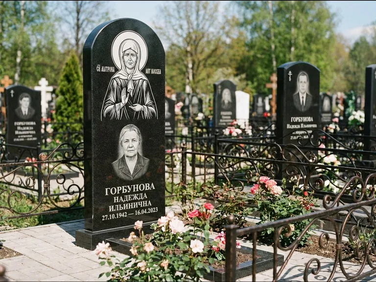 Памятник с гравировкой иконы: стела с арочным верхом и киотом под образ — гравировка образа Матроны Московской, гранитный цоколь с тёмной плиткой, работа «Ковалёв» в Челябинске