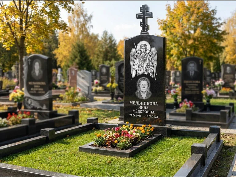 Памятник с гравировкой иконы: округлая стела-медальон с ликом — гравировка Богородицы «Семистрельная», луговые травы и полевые цветы за участком, работа «Гущин» в Челябинске