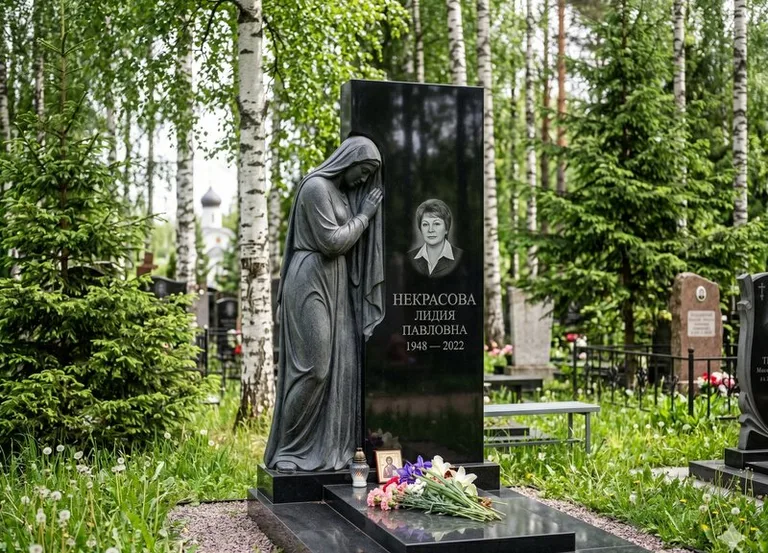 Гранитная фигура скорбящего мужчины у чёрной стелы в Челябинске